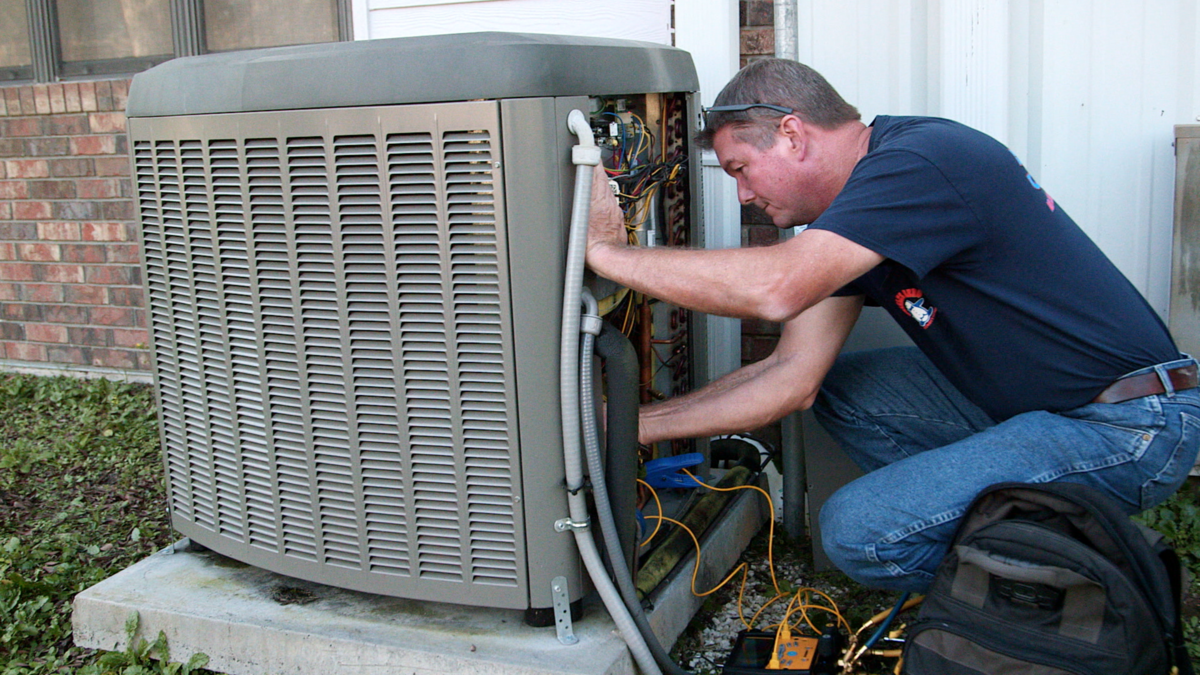 Technician repairing an outdoor air conditioning unit